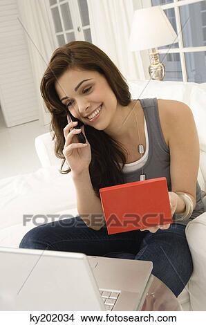 Woman shopping online and talking on a mobile phone View Large Photo Image Picture - Woman shopping online and talking on a mobile phone. Fotosearch