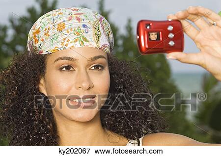 Woman taking a picture of herself with a digital camera View Large Photo Image Stock Photo - Woman taking a picture of herself with a digital camera. Fotosearch
