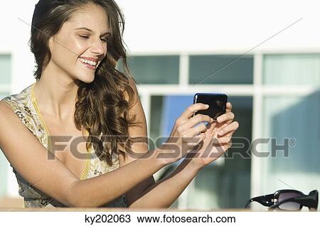 Woman taking a picture with a mobile phone and smiling View Large Photo Image Stock Image - Woman taking a picture with a mobile phone and smiling. Fotosearch