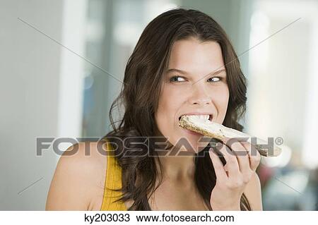 Close-up of a woman eating a bread View Large Photo Image Stock Image - Close-up of a woman eating a bread. Fotosearch