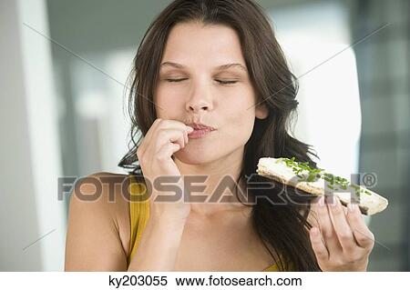 Close-up of a woman eating a bread View Large Photo Image Stock Photography - Close-up of a woman eating a bread. Fotosearch