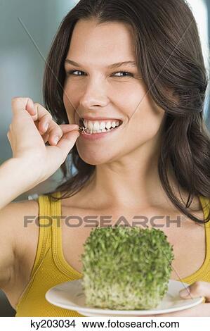 Picture - Woman eating bean sprouts and smiling. Fotosearch