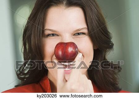 Woman holding a nectarine in front of her nose View Large Photo Image Stock Photograph - Woman holding a nectarine in front of her nose. Fotosearch