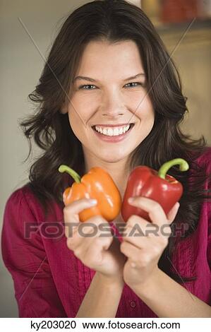 Woman holding an orange and a red bell pepper View Large Photo Image Stock Image - Woman holding an orange and a red bell pepper. Fotosearch