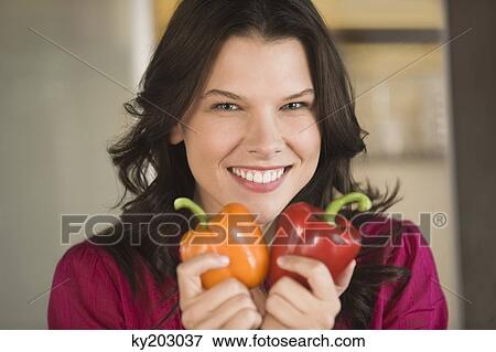 Woman holding an orange and a red bell pepper View Large Photo Image Stock Photo - Woman holding an orange and a red bell pepper. Fotosearch