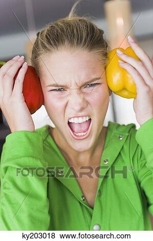 Woman holding bell peppers on her temples and shouting View Large Photo Image Stock Photo - Woman holding bell peppers on her temples and shouting. Fotosearch