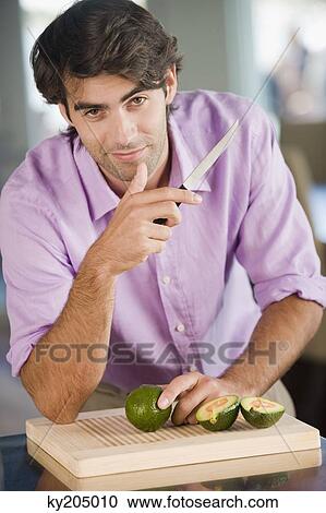 Portrait of a man cutting avocado View Large Photo Image Stock Image - Portrait of a man cutting avocado. Fotosearch