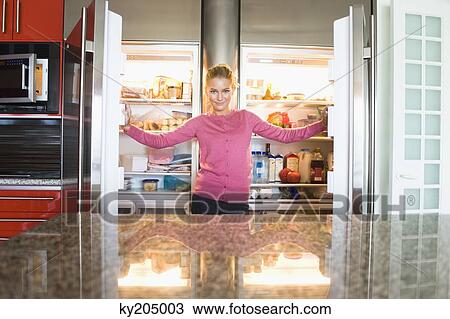 Portrait of a woman standing in front of a refrigerator View Large Photo Image Stock Image - Portrait of a woman standing in front of a refrigerator. Fotosearch