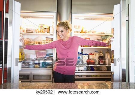 Portrait of a woman standing in front of a refrigerator View Large Photo Image Stock Image - Portrait of a woman standing in front of a refrigerator. Fotosearch