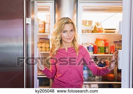 Portrait of a woman standing in front of a refrigerator View Large Photo Image Stock Photo - Portrait of a woman standing in front of a refrigerator. Fotosearch
