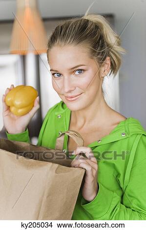 Portrait of a woman taking out yellow pepper from a paper bag View Large Photo Image Picture - Portrait of a woman taking out yellow pepper from a paper bag. Fotosearch