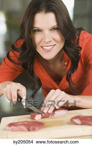 Picture - Woman cutting meat slices. Fotosearch