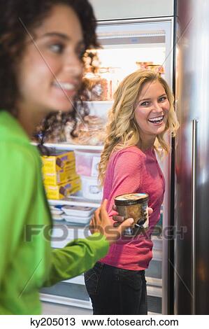 Woman giving a food can to her friend from a refrigerator View Large Photo Image Stock Image - Woman giving a food can to her friend from a refrigerator. Fotosearch