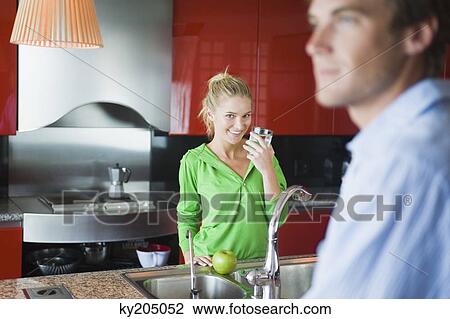 Woman holding a glass of water in the kitchen View Large Photo Image Stock Image - Woman holding a glass of water in the kitchen. Fotosearch
