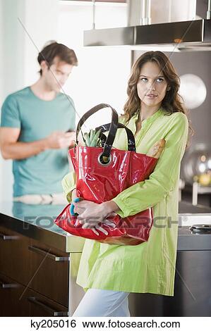 Woman holding a shopping bag in the kitchen View Large Photo Image Stock Photograph - Woman holding a shopping bag in the kitchen. Fotosearch