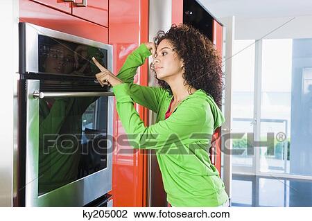 Woman leaning against an oven in the kitchen View Large Photo Image Stock Image - Woman leaning against an oven in the kitchen. Fotosearch