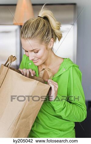 Woman looking into a paper bag View Large Photo Image Stock Image - Woman looking into a paper bag. Fotosearch