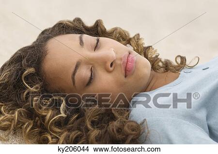 Close-up of a girl lying in sand View Large Photo Image Picture - Close-up of a girl lying in sand. Fotosearch