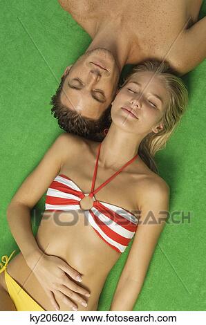 High angle view of a couple sunbathing View Large Photo Image Picture - High angle view of a couple sunbathing. Fotosearch