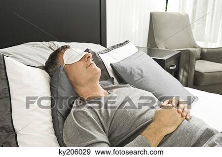 Man sleeping in bed wearing an eye mask View Large Photo Image Stock Photo - Man sleeping in bed wearing an eye mask. Fotosearch