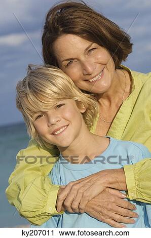 Woman hugging her grandson from behind on the beach View Large Photo Image Stock Image - Woman hugging her grandson from behind on the beach. Fotosearch