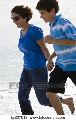 Woman running on the beach with her grandson View Large Photo Image Stock Image - Woman running on the beach with her grandson. Fotosearch