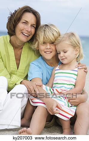 Woman sitting with her grandchildren on the beach View Large Photo Image Stock Image - Woman sitting with her grandchildren on the beach. Fotosearch
