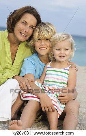 Woman sitting with her grandchildren on the beach View Large Photo Image Stock Image - Woman sitting with her grandchildren on the beach. Fotosearch