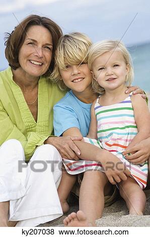 Woman sitting with her grandchildren on the beach View Large Photo Image Stock Photo - Woman sitting with her grandchildren on the beach. Fotosearch