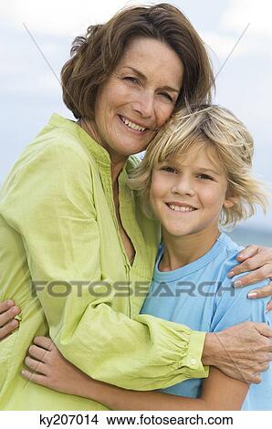 Picture - Woman smiling with her grandson on the beach. Fotosearch
