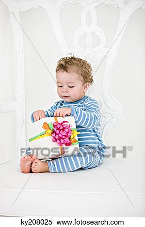 Baby boy playing with a present in an armchair View Large Photo Image Stock Photography - Baby boy playing with a present in an armchair. Fotosearch
