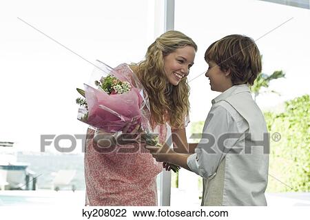 Stock Image - Boy giving a bouquet of flowers to her mother. Fotosearch