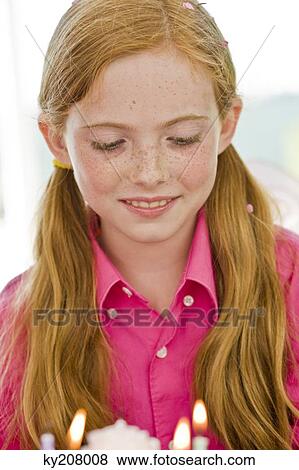 Stock Photo - Close-up of a girl looking at a birthday cake. Fotosearch