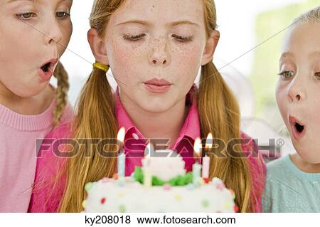 Stock Photo - Close-up of three girls blowing out candles on a birthday cake. Fotosearch