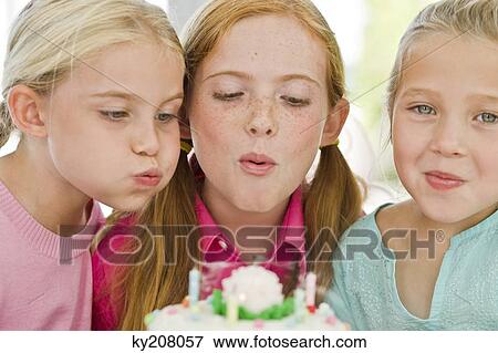 Stock Photo - Close-up of three girls blowing out candles on a birthday cake. Fotosearch