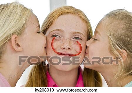 Close-up of two girls kissing their friend View Large Photo Image Stock Image - Close-up of two girls kissing their friend. Fotosearch
