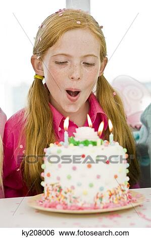 Stock Photograph - Girl blowing out candles on a birthday cake. Fotosearch