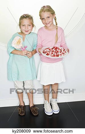 Girl holding a plate of jelly beans with her friend standing beside her View Large Photo Image Stock Photo - Girl holding a plate of jelly beans with her friend standing beside her. Fotosearch