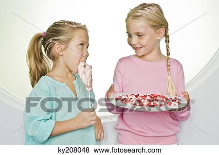 Girl holding a plate of jelly beans with her friend eating a lollipop beside her View Large Photo Image Stock Photo - Girl holding a plate of jelly beans with her friend eating a lollipop beside her. Fotosearch