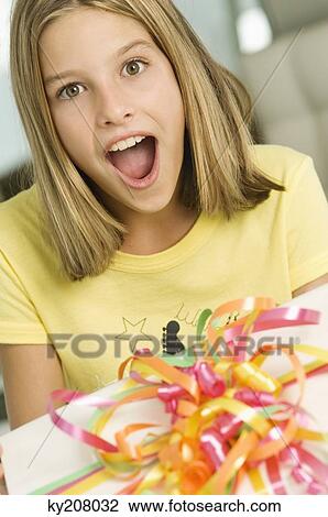 Girl looking at a birthday present with a surprise View Large Photo Image Stock Image - Girl looking at a birthday present with a surprise. Fotosearch