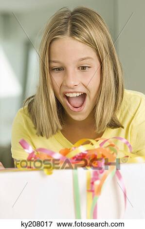 Stock Photo - Girl looking at a birthday present with a surprise. Fotosearch