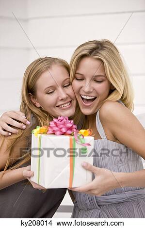 Woman giving a present to her friend View Large Photo Image Picture - Woman giving a present to her friend. Fotosearch