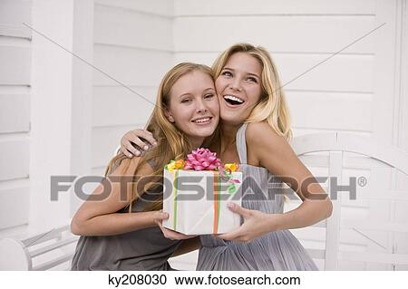 Woman giving a present to her friend View Large Photo Image Stock Image - Woman giving a present to her friend. Fotosearch