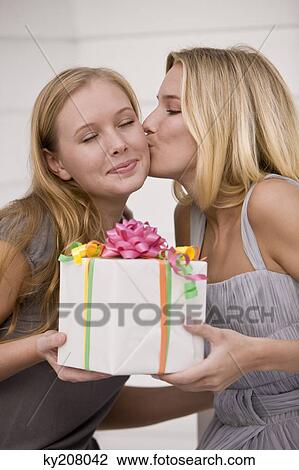 Woman giving a present to her friend and kissing View Large Photo Image Stock Image - Woman giving a present to her friend and kissing. Fotosearch