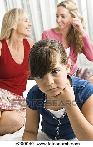 Girl looking sad with her parents sitting behind her View Large Photo Image Stock Image - Girl looking sad with her parents sitting behind her. Fotosearch
