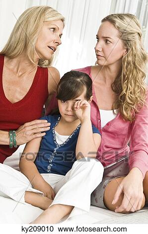 Stock Image - Girl sitting with her parents and looking sad. Fotosearch