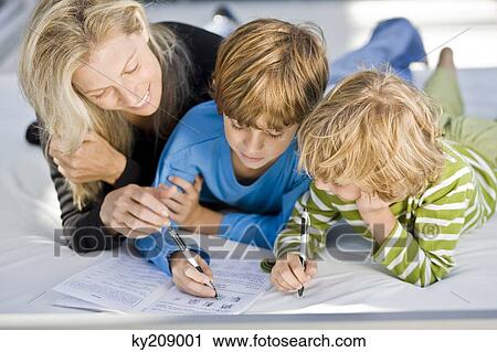 Stock Image - Woman helping her sons in their homework. Fotosearch