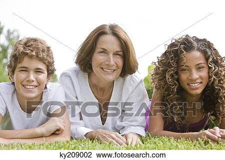 Woman lying on grass with her grandchildren View Large Photo Image Stock Image - Woman lying on grass with her grandchildren. Fotosearch