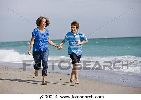 Woman running on the beach with her grandson View Large Photo Image Picture - Woman running on the beach with her grandson. Fotosearch