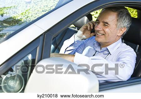 Man sitting in a car and talking on a mobile phone View Large Photo Image Stock Photo - Man sitting in a car and talking on a mobile phone. Fotosearch